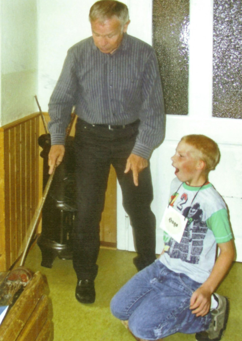 Herbert Greb erklärte einem Schüler die Strafen, die es früher für Ungehorsamkeit gab. Unser Bild zeigt den Jungen wie er mit den Knien auf der spitzen Seite eines Buchenholzscheites “Platz nehmen muss” (Bild von 2013).<br />Repro: Winterholler